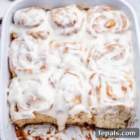 Greek Yogurt Cinnamon Rolls: Soft, Tangy, Homemade 9 cinnamon rolls in cream cheese frosting in a baking dish.