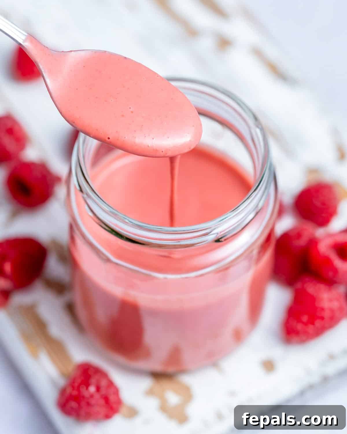 A jar filled with raspberry vinaigrette with spoon in jar.