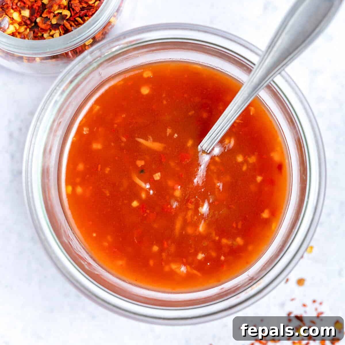 sweet chili sauce in a jar with spoon in the jar.
