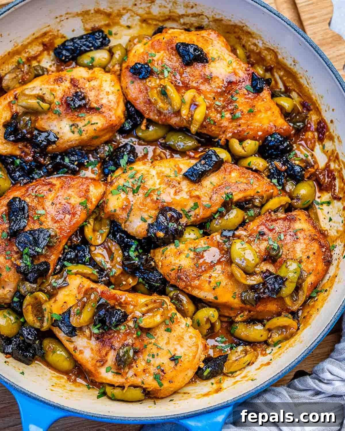 Savory Chicken Marbella with Olives and Prunes 7 chicken in marbella sauce with prunes and olives in a skillet.
