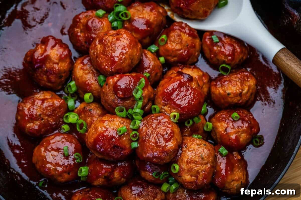 chicken meatballs in tomato jelly sauce in a pan.