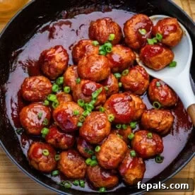 meatballs in a grape jelly tomato sauce in a skillet.