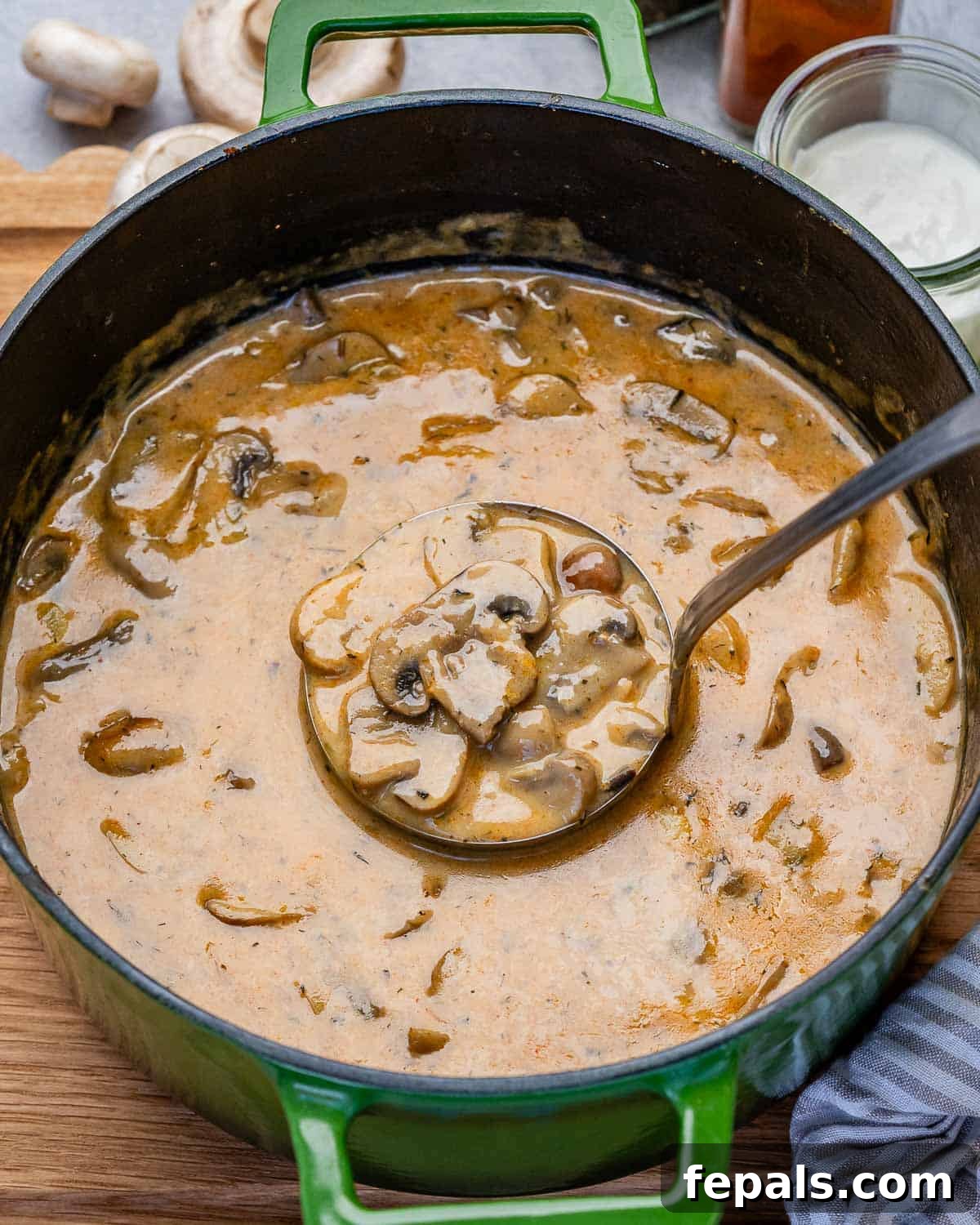 A green pot of Hungarian mushroom soup with a ladle in it