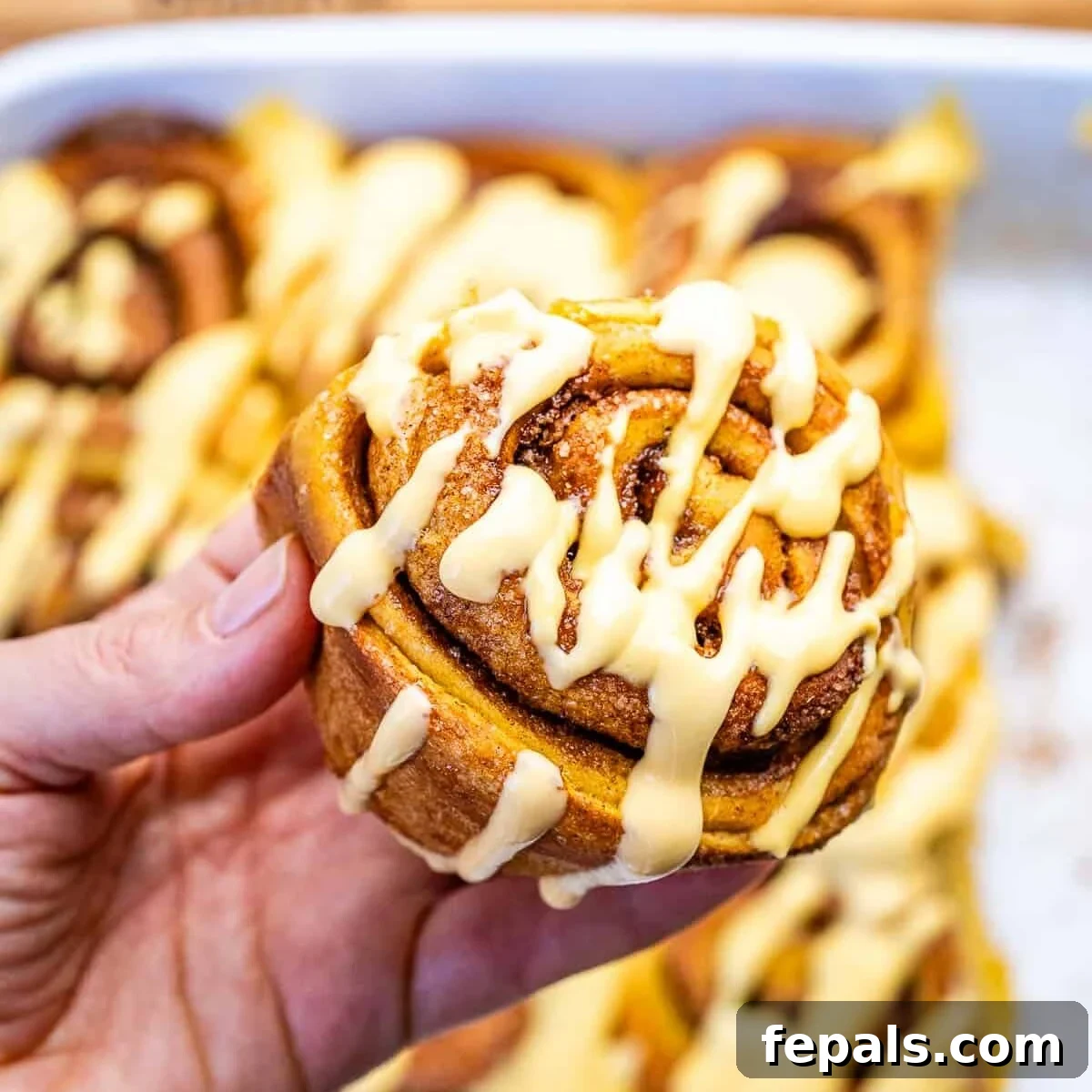 hand holding a pumpkin cinnamon roll.
