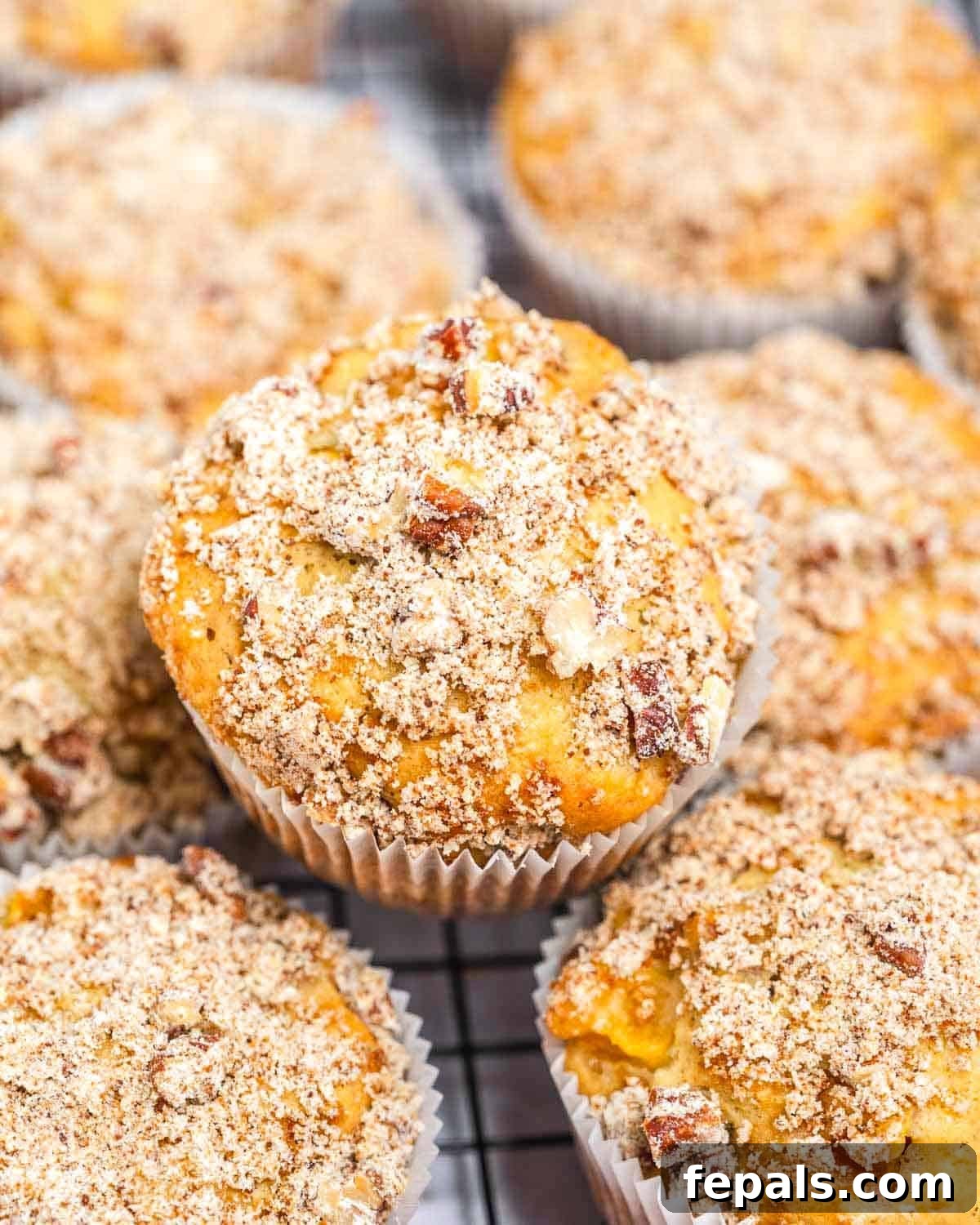 Moist Greek Yogurt Peach Muffins with Fresh Peaches 2 peach muffins stacked over each other on a cooling rack.