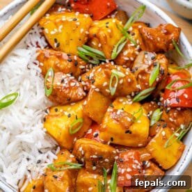 sweet and sour chicken served over rice in a bowl.