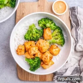 a round bowl with rice, topped with broccoli and bang bang salmon bites.