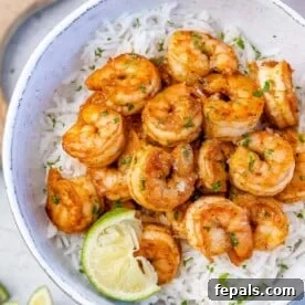top view of cajun shrimp over a rice of white bowl with a lime wedge for garnish