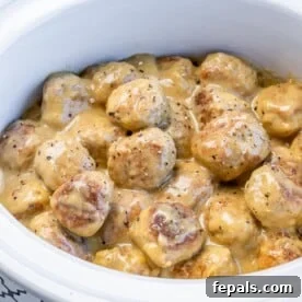 side close up shot of a white crockpot with creamy Swedish meatballs